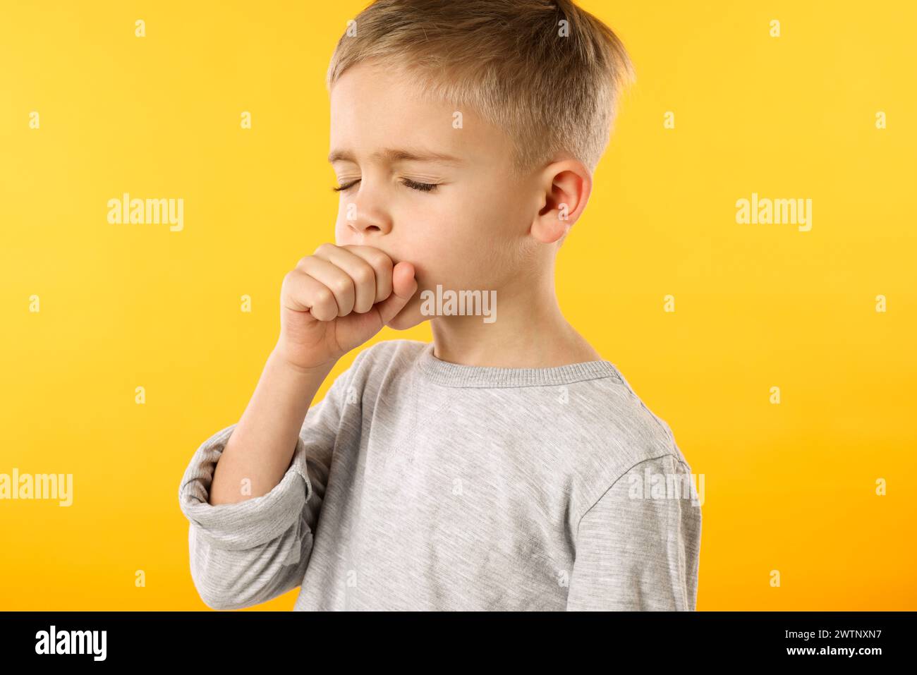 Sick boy coughing on yellow background. Cold symptoms Stock Photo Alamy