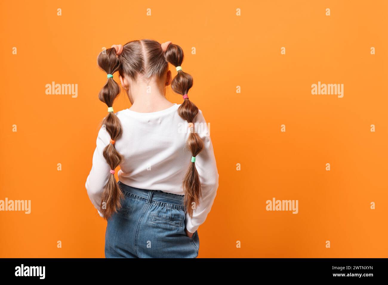 little-girl-with-beautiful-hairstyle-on-orange-background-back-view