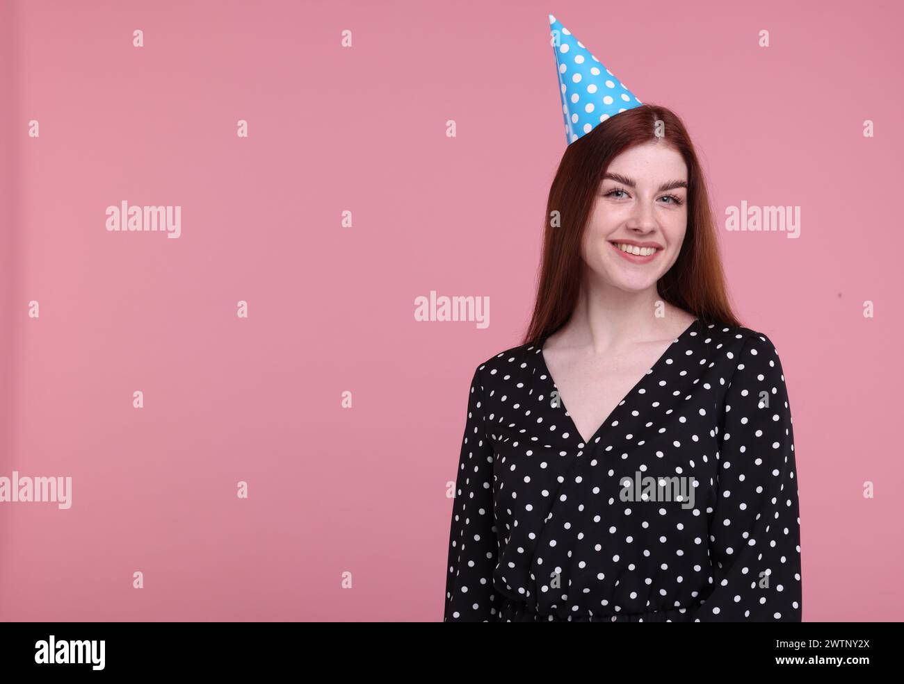 Happy woman in party hat on pink background, space for text Stock Photo