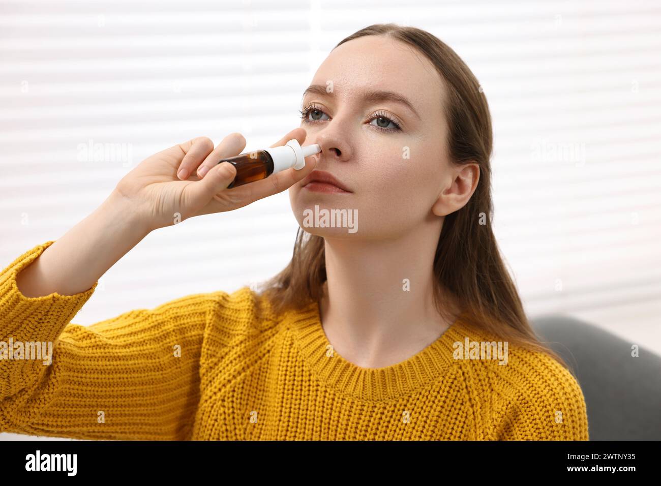 Medical drops. Young woman using nasal spray indoors Stock Photo