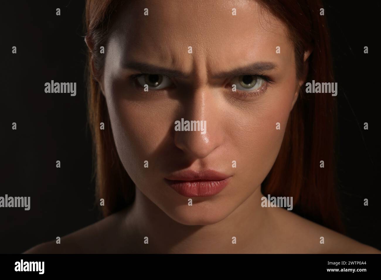 Evil eye. Young woman with scary eyes on black background, closeup Stock Photo