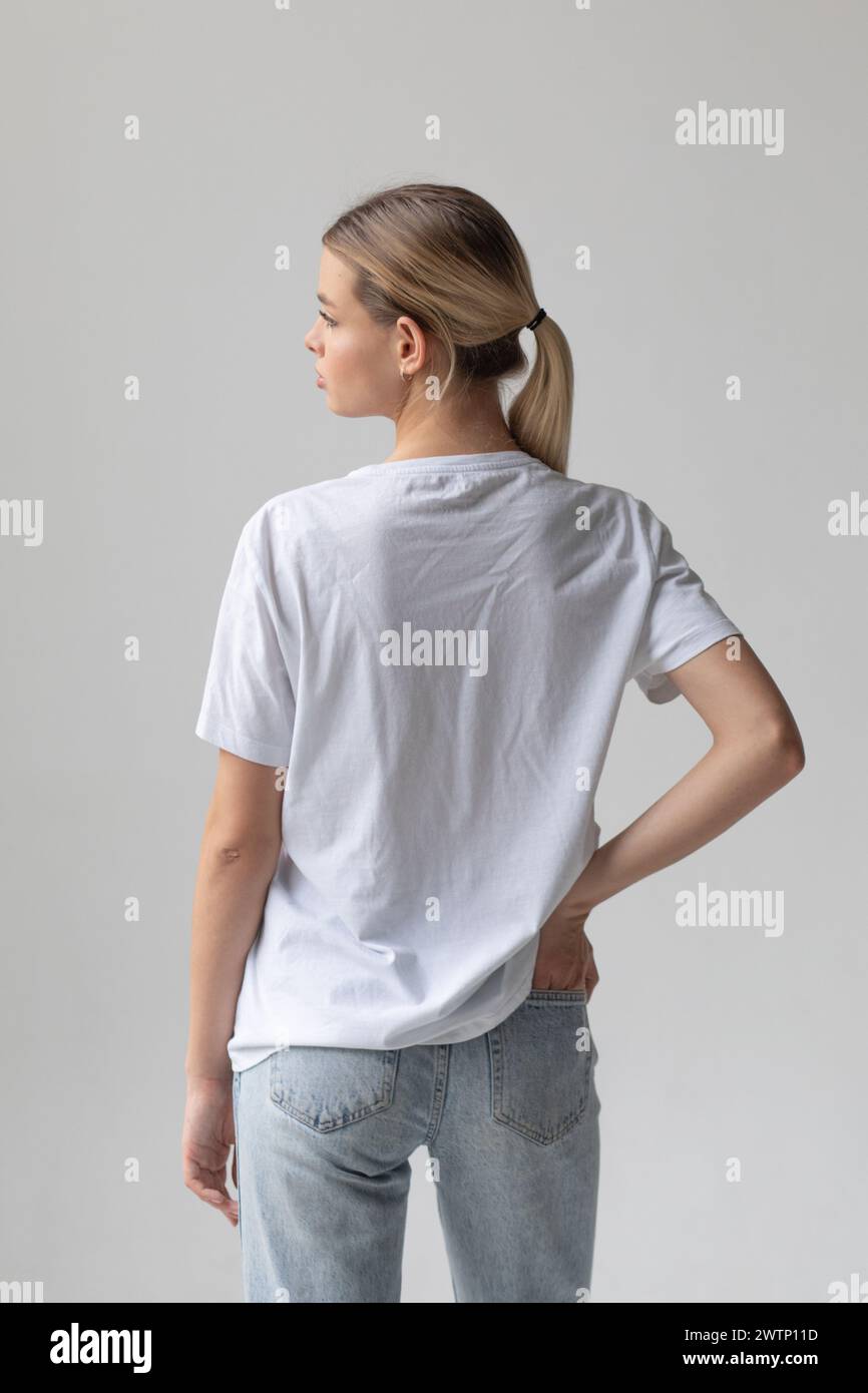 Beautiful blonde woman in a white T-shirt and blue jeans posing on a ...