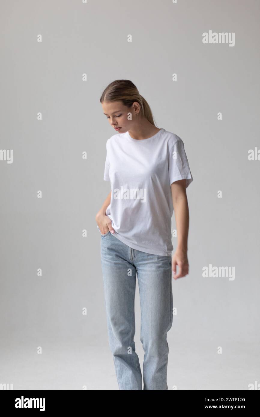 Beautiful blonde woman in a white T-shirt and blue jeans posing on a ...