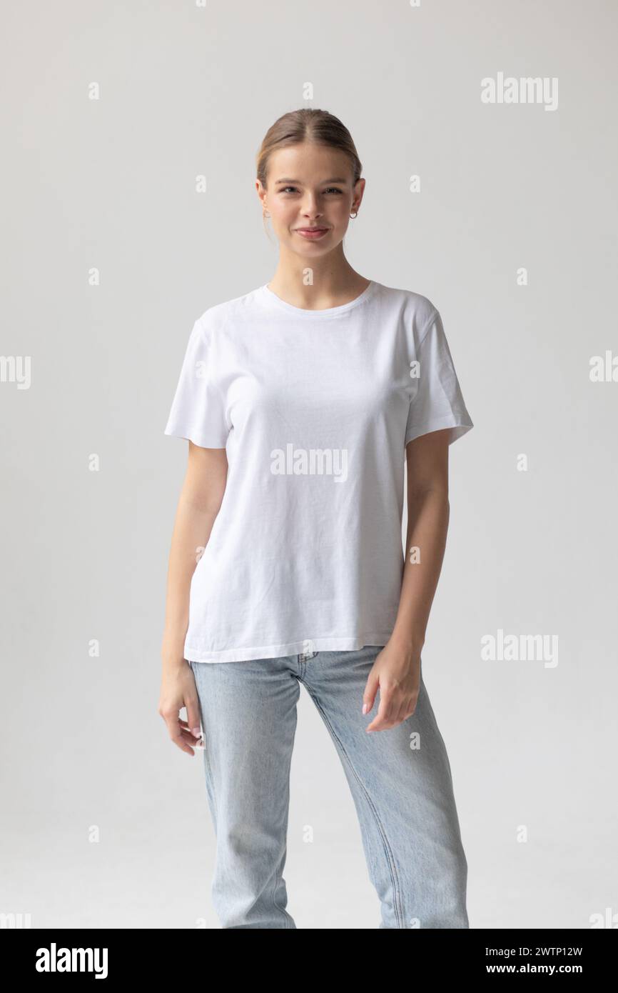Beautiful blonde woman in a white T-shirt and blue jeans posing on a ...