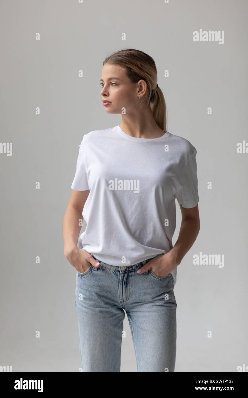 Beautiful blonde woman in a white T-shirt and blue jeans posing on a ...