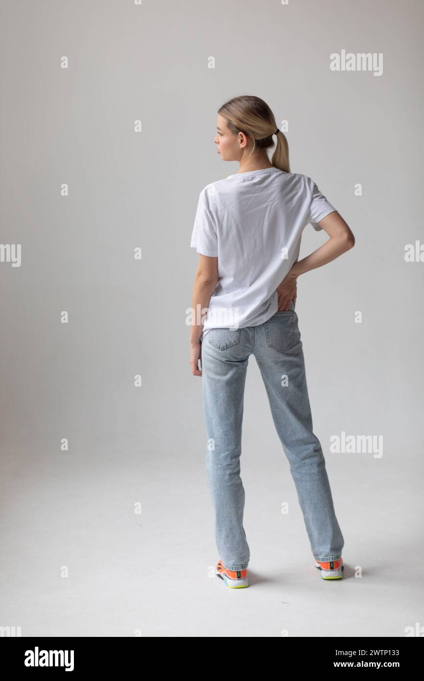 Beautiful blonde woman in a white T-shirt and blue jeans posing on a ...