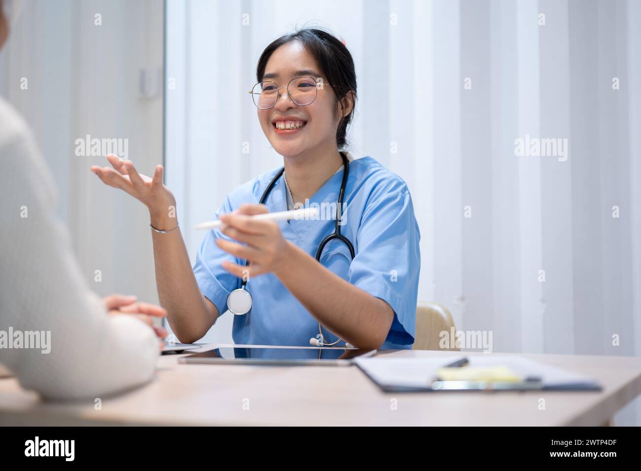 An Asian female doctor is giving advice and talking with a patient in ...