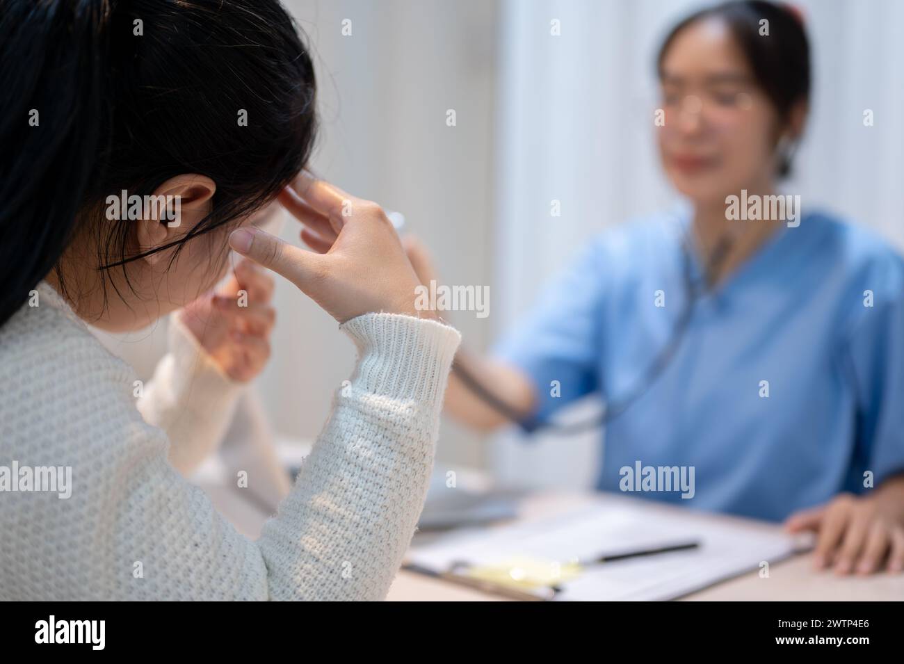 A stressed Asian female patient expressing concern about her health problems while discussing the treatment plan with a doctor at the hospital. health Stock Photo