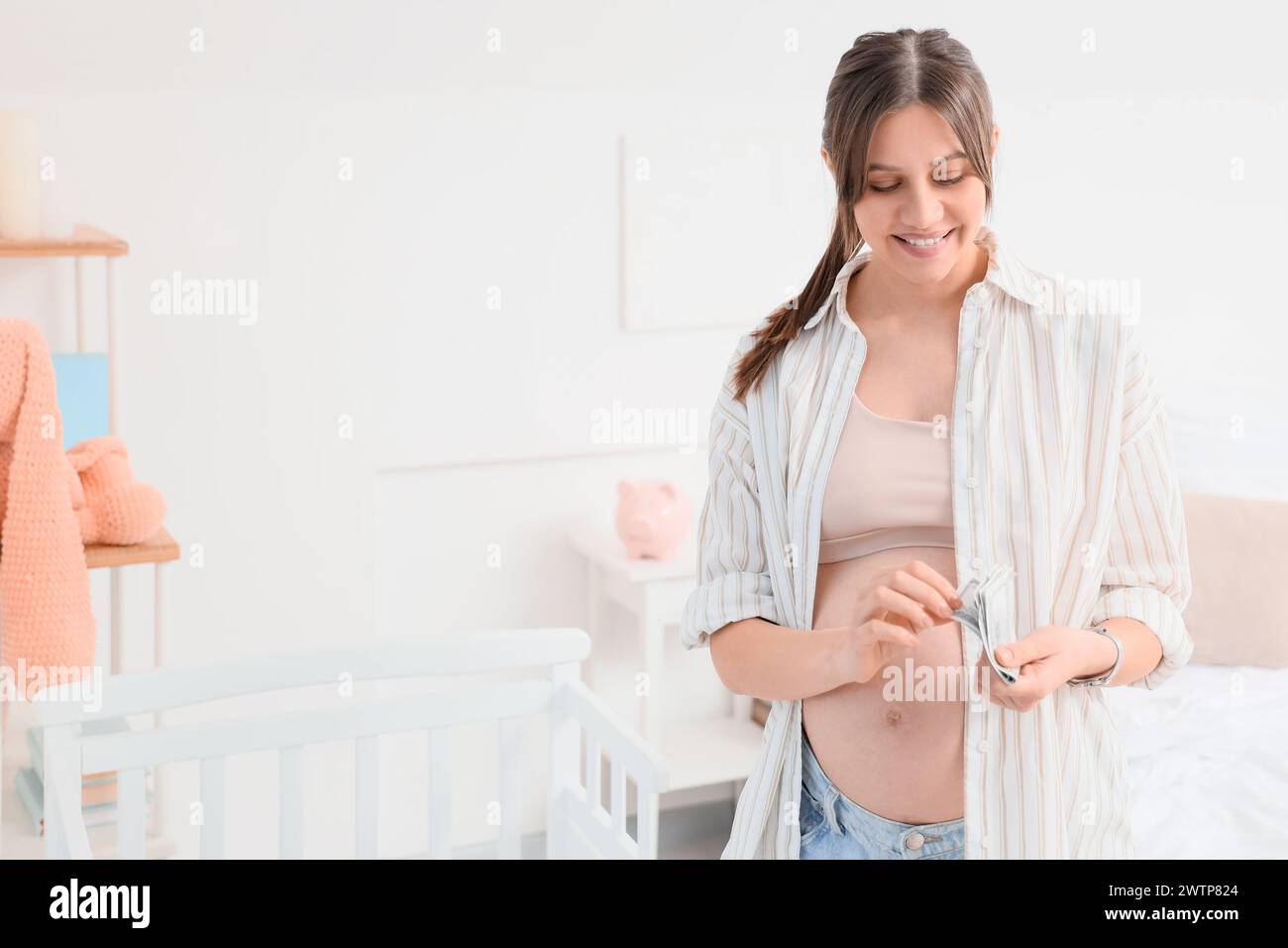 Young pregnant woman with money in bedroom. Maternal Benefit concept Stock Photo