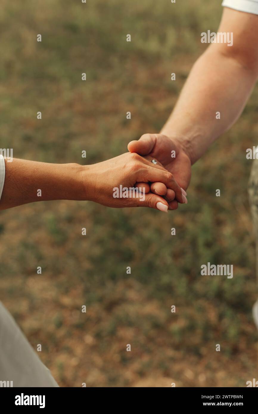A detailed view of two individuals connecting by holding hands. Stock Photo