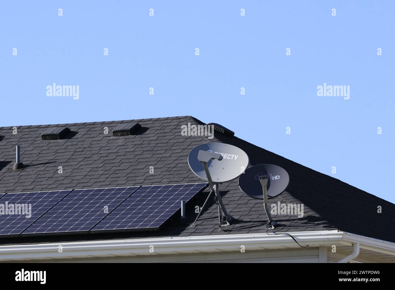 Direct TV satellite Dishes on a roof with solar panels Stock Photo