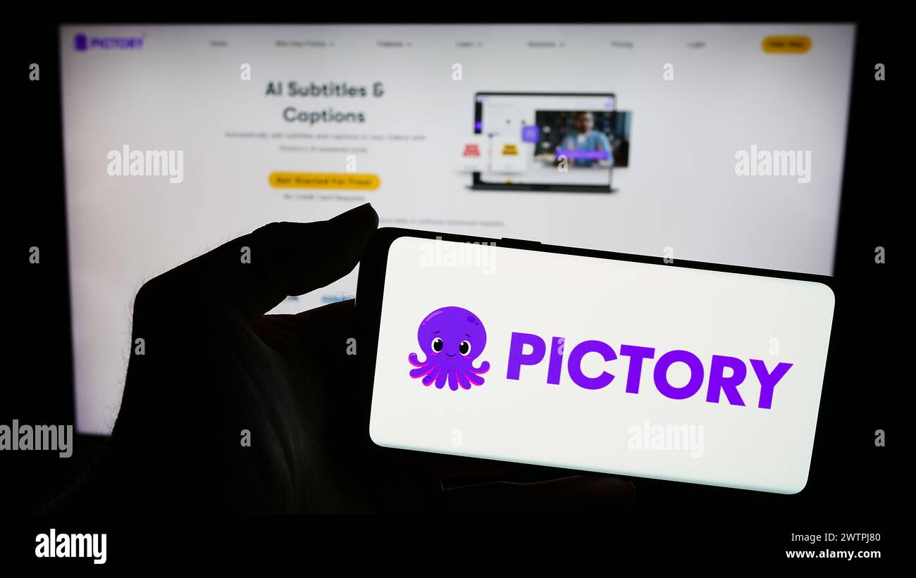 Person holding mobile phone with logo of American video creation company Pictory Corp. in front of business web page. Focus on phone display. Stock Photo