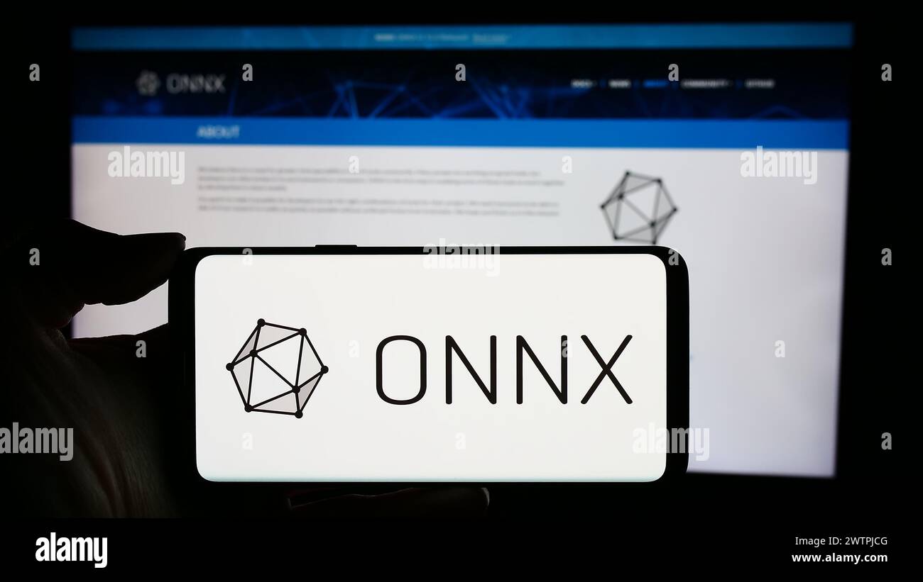Person holding cellphone with logo of AI ecosystem Open Neural Network Exchange (ONNX) in front of webpage. Focus on phone display. Stock Photo