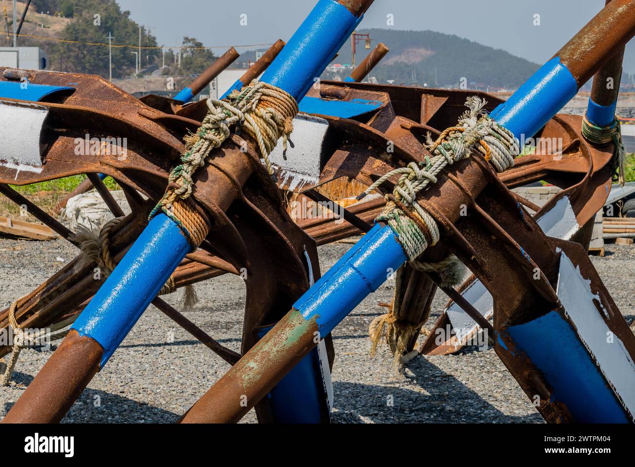 Cluster of rusted metal anchors with blue and white stripes tied with ...
