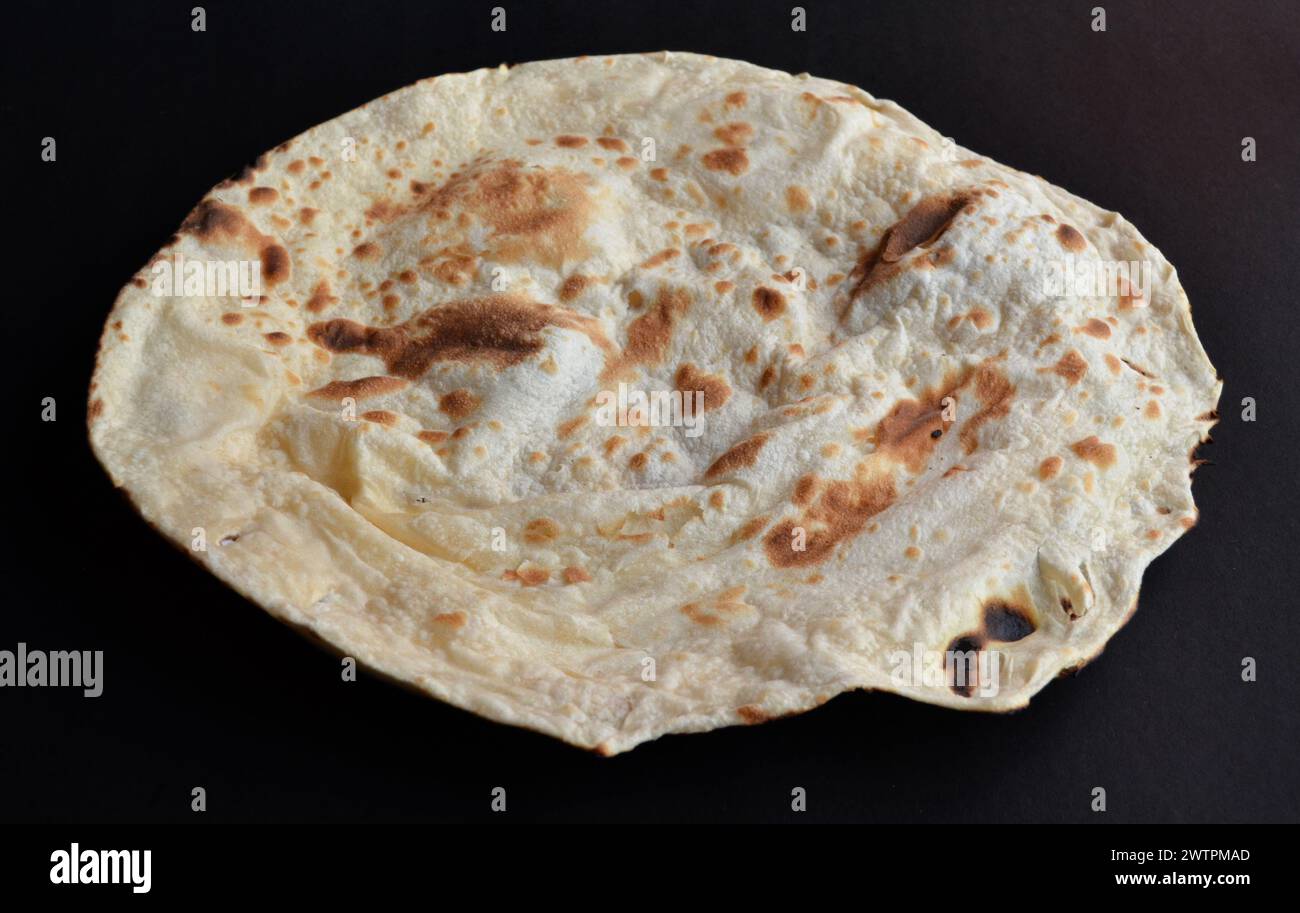 Irani roti is a flatbread made with whole wheat and traditionally cooked in tandoor.a close-up view isolated in a black background. Stock Photo