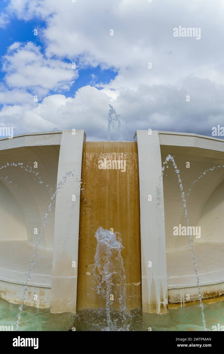 Public fountain with water jets with a blue sky with clouds Stock Photo