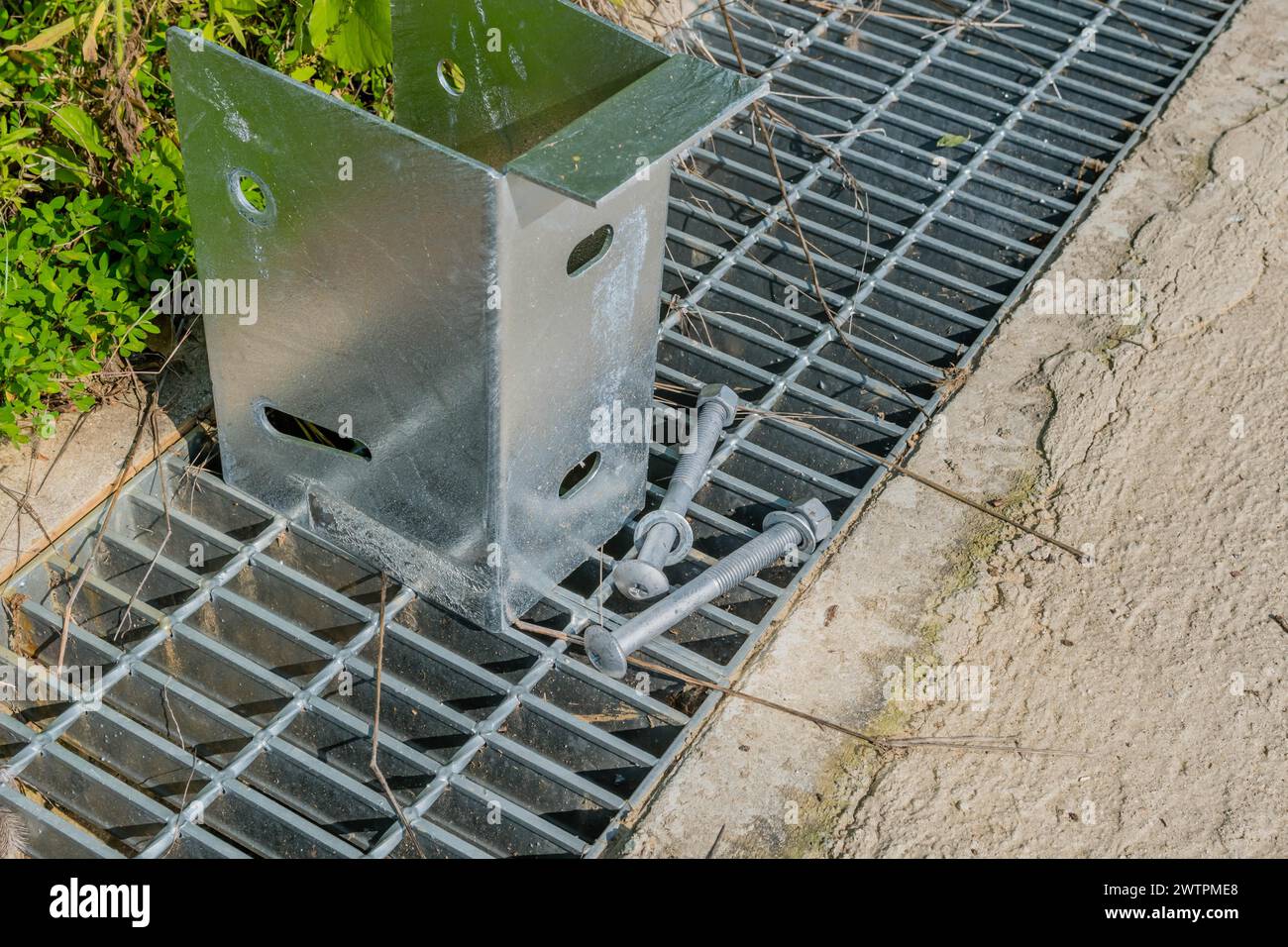 A close-up of a metal bracket support with screws on a steel grate, in Daejeon, South Korea Stock Photo