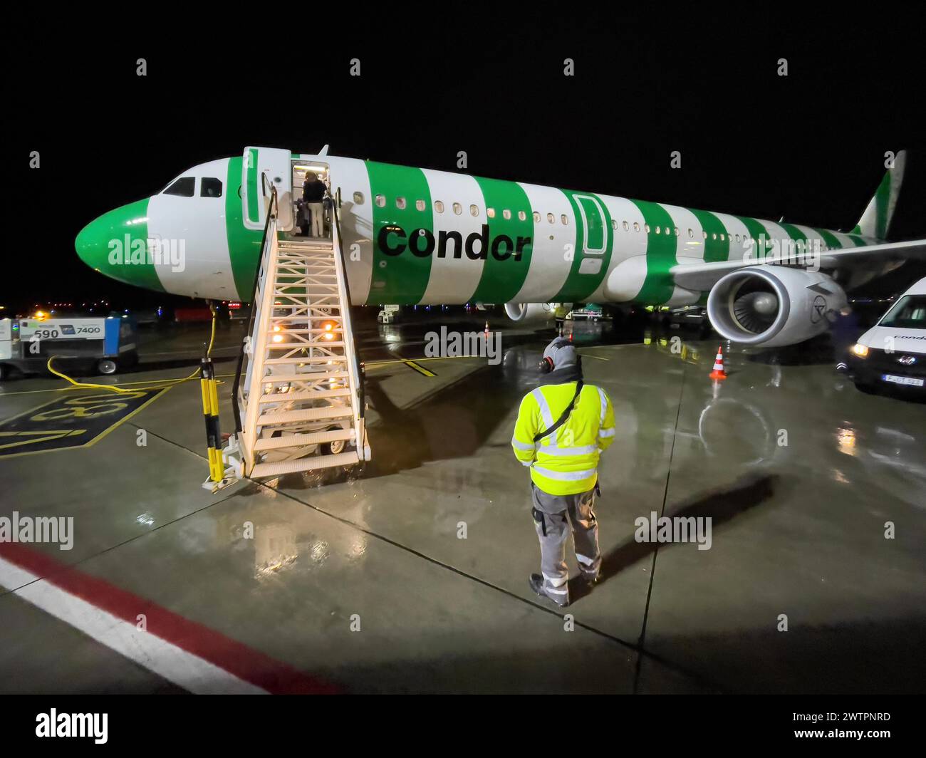 Night shot of Condor aircraft plane Airbus A321 standing landed in parking position on apron apron of airport with mobile stairs for passengers Stock Photo