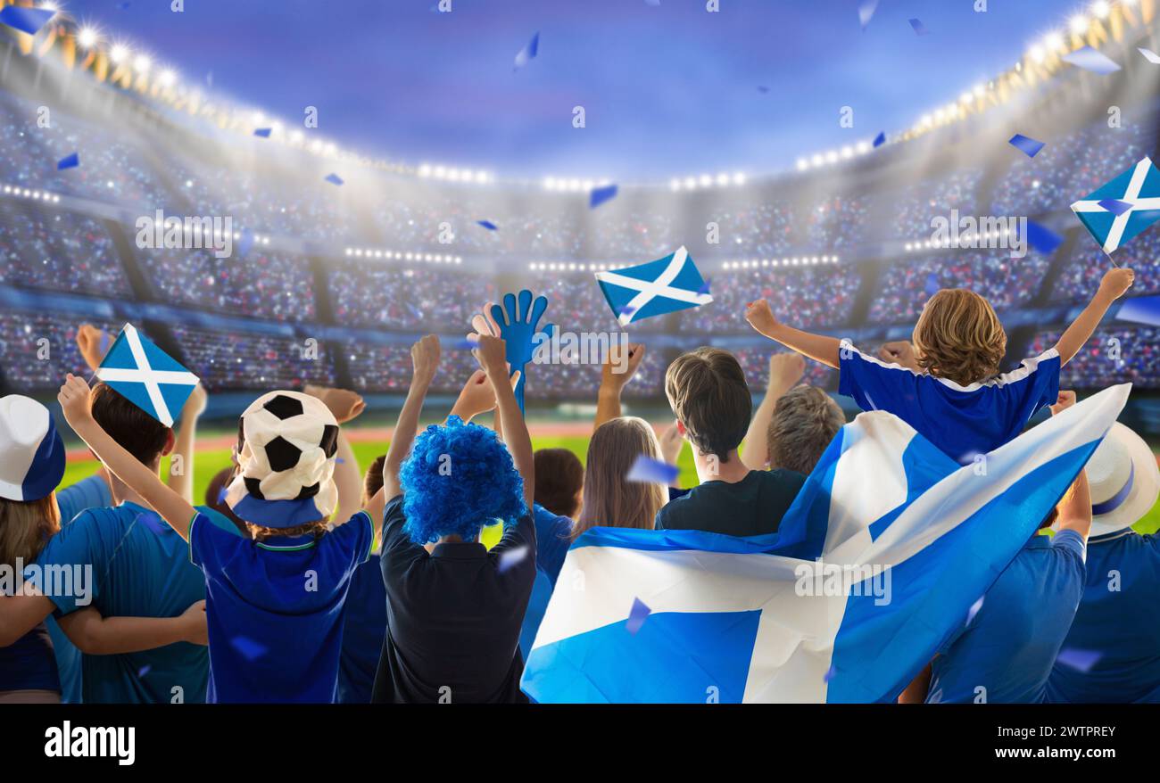 Scotland football supporter on stadium. Scottish fans on soccer pitch watching team play. Group of Scotland supporters with flag and national jersey Stock Photo