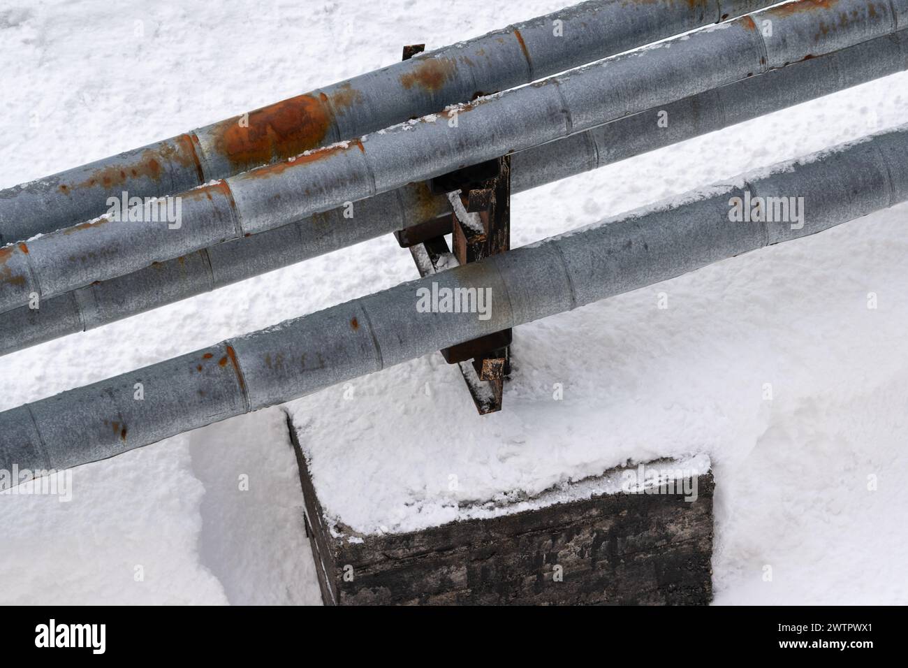 External city central heating pipes, with old rusty thermal insulation jackets, laid above ground. Pipes protected by rusty thermal insulation jacket Stock Photo