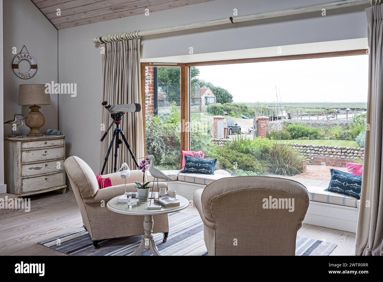 Telescope in picture window with view of coastal Blakeney, Norfolk, UK Stock Photo