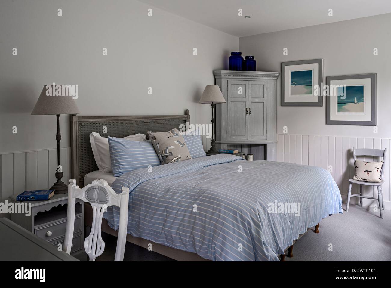 Blue and white striped duvet and seascapes in British home in Blakeney, Norfolk, UK Stock Photo