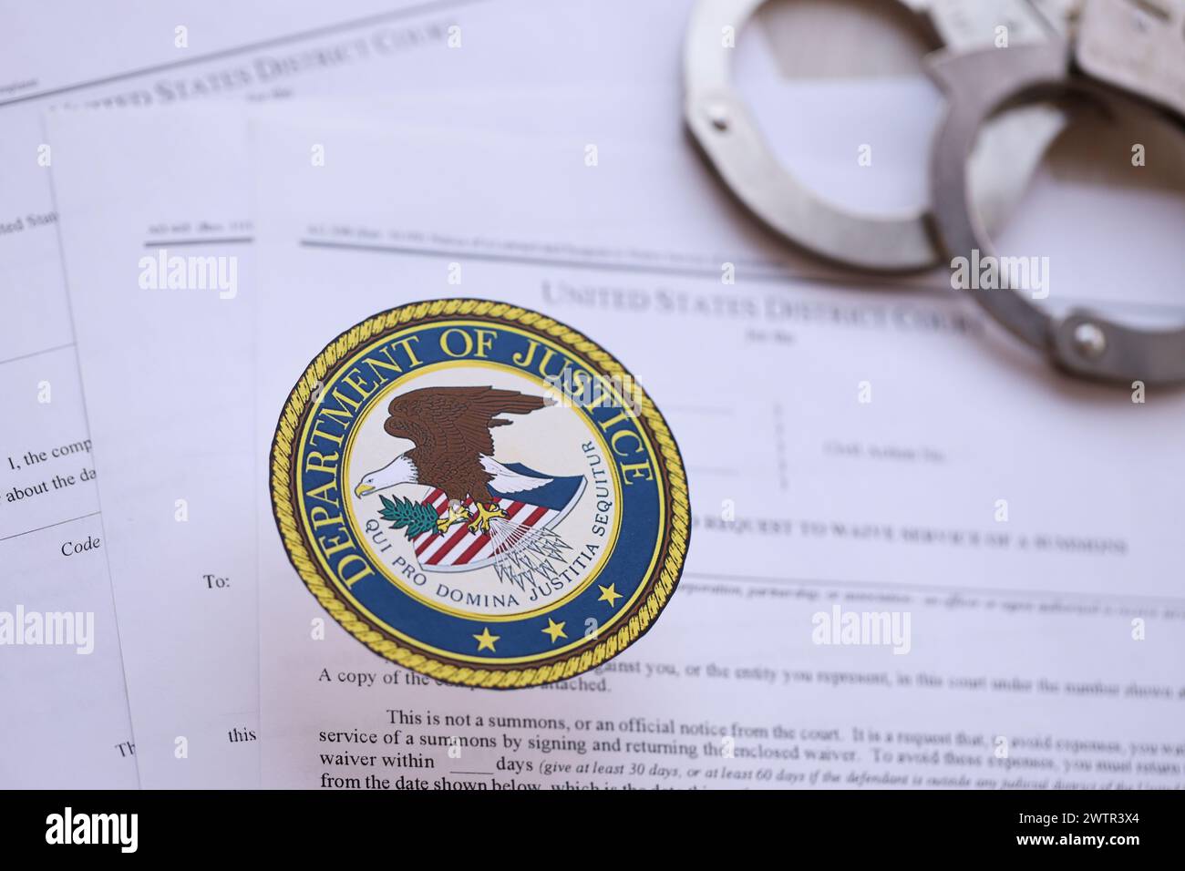 KYIV, UKRAINE - MARCH 9, 2024 US Department of Justice seal with handcuffs on many US District Court warrants and complaints close up Stock Photo