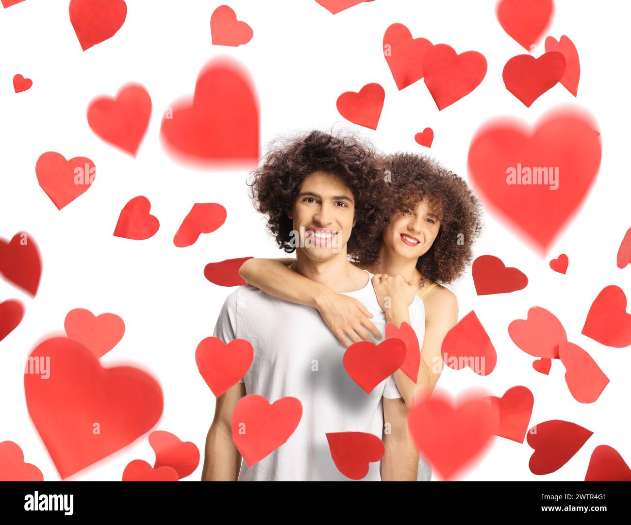 Young man and woman with curly hair in embrace standing under red hearts isolated on white background Stock Photo