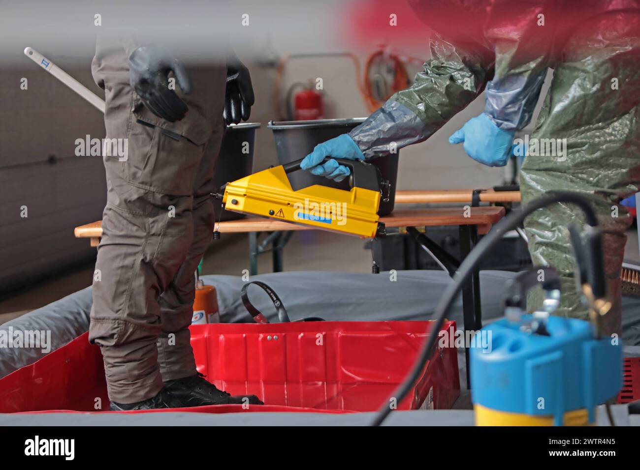 Beamte des Spezialeinsatzkommandos der bayerischen Polizei SEK in Schutzkleidung werden in einer von der Feuerwehr eingerichteten Station zur Dekontaminierung von der Feuerwehr mit Messgeräten überprüft und nach Sicherung und Ablegung der persönlichen Schutzausrüstung dekontaminiert. Länderübergreifende Großübung der Spezialeinheiten Counter Terrorism Exercise CTE 2024. Sulzbach-Rosenberg Bayern Deutschland *** Officers of the Bavarian police special task force SEK in protective clothing are checked by the fire department with measuring equipment in a decontamination station set up by the fire Stock Photo