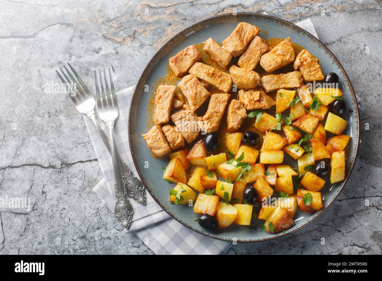 Portuguese dish Rojoes Minhota of fried pork cubes with with potato side dish closeup on the plate on the table. Horizontal top view from above Stock Photo