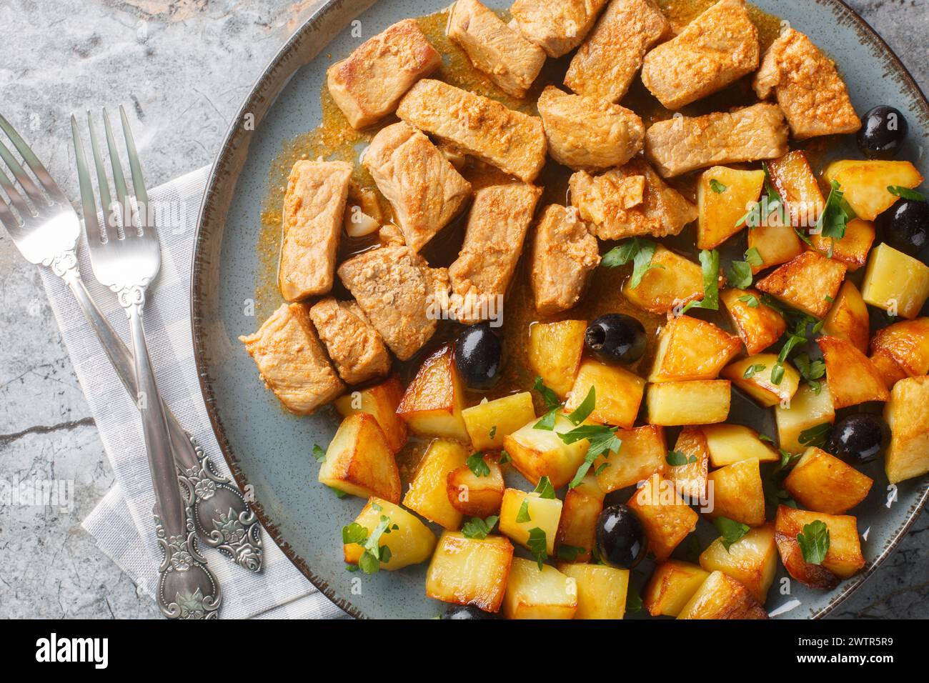 Rojoes Portuguese dish of fried pork cubes and potatoes closeup on the plate on the table. Horizontal top view from above Stock Photo