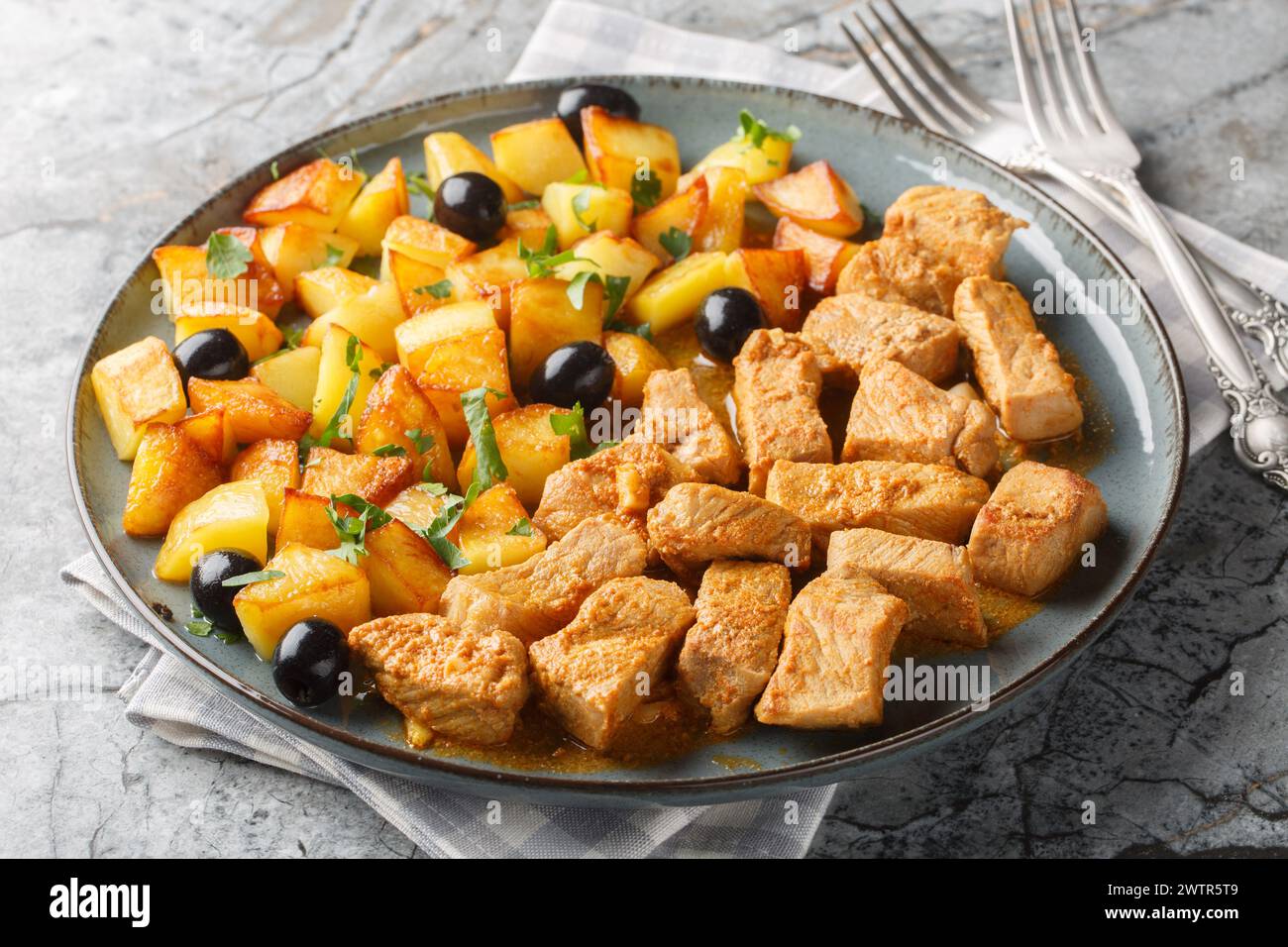 Portuguese dish Rojoes Minhota of fried pork cubes with with potato side dish closeup on the plate on the table. Horizontal Stock Photo