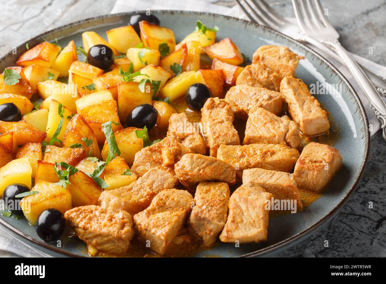 Rojoes Portuguese dish of fried pork cubes and potatoes closeup on the plate on the table. Horizontal Stock Photo