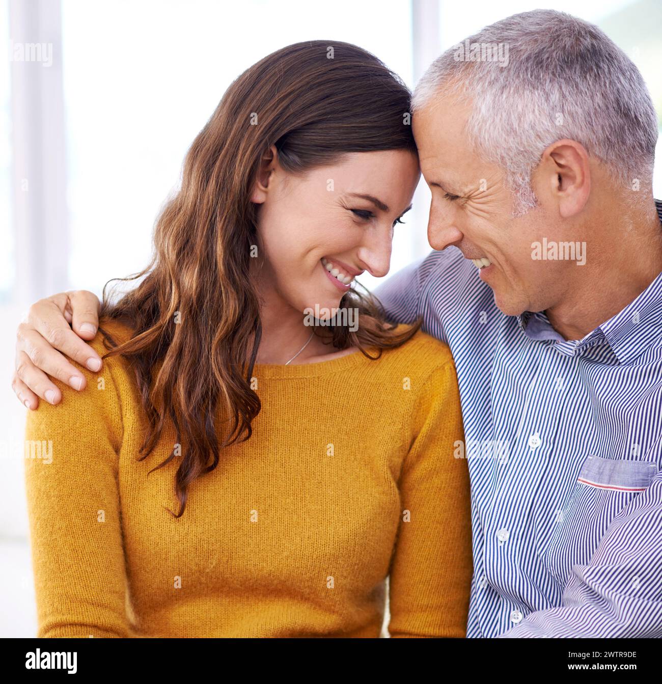 Couple, laughing and hug in home for love with support, funny joke and comfort in living room of house. Senior man, woman and smile with face for Stock Photo