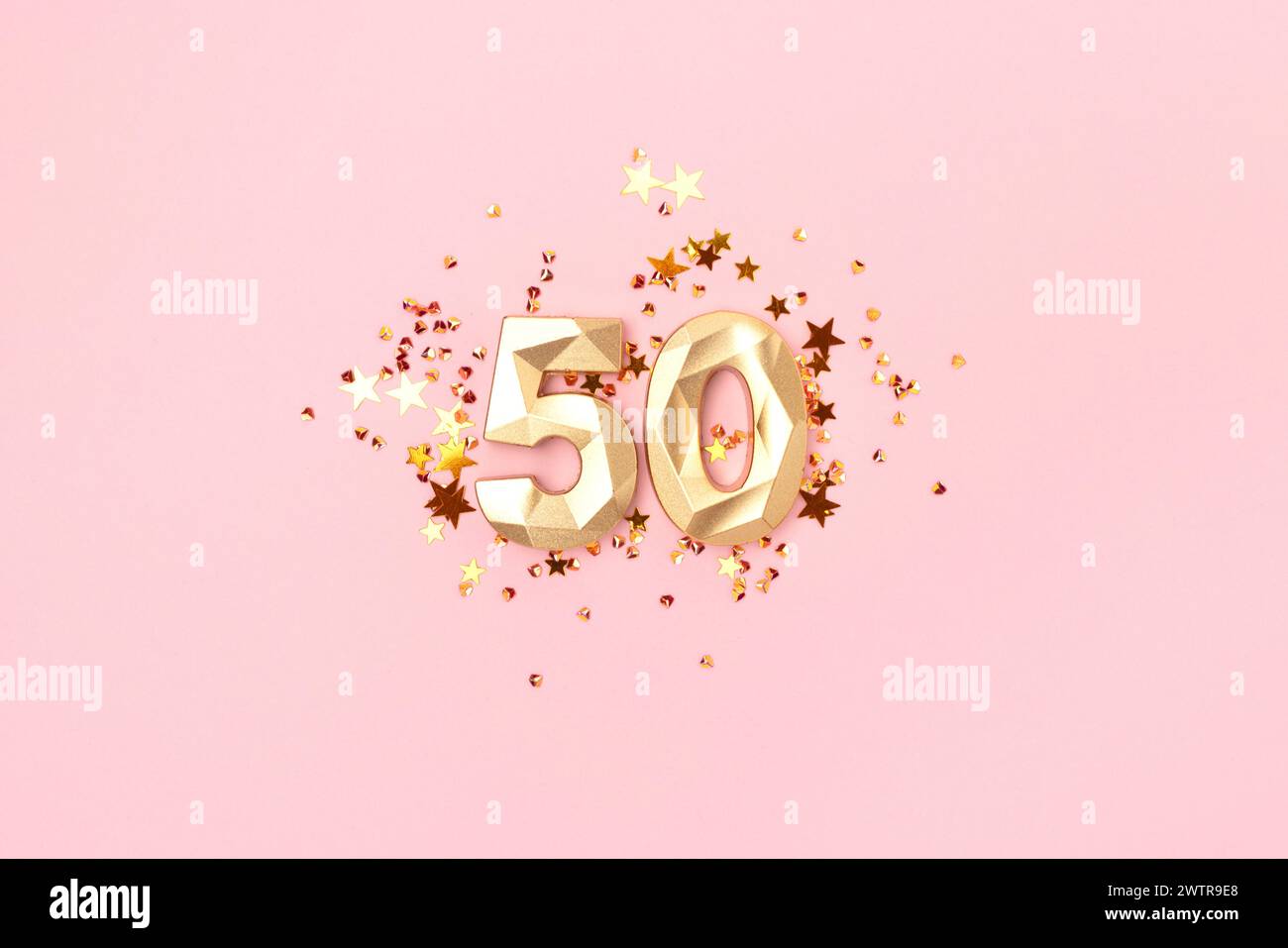 Gold colored number 50 and stars confetti on a pink background. Creative concept. Stock Photo