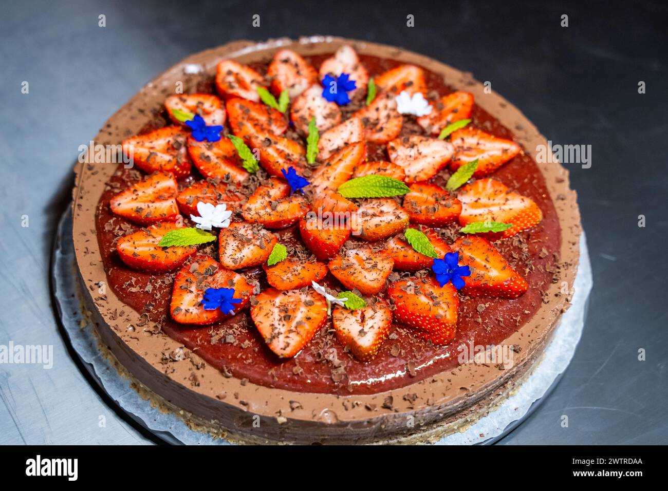Chocolate cake with strawberries and blue flowers on top Stock Photo ...