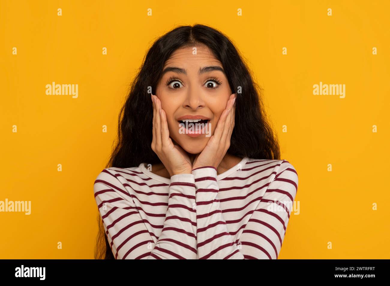 Young woman surprised expression on yellow Stock Photo