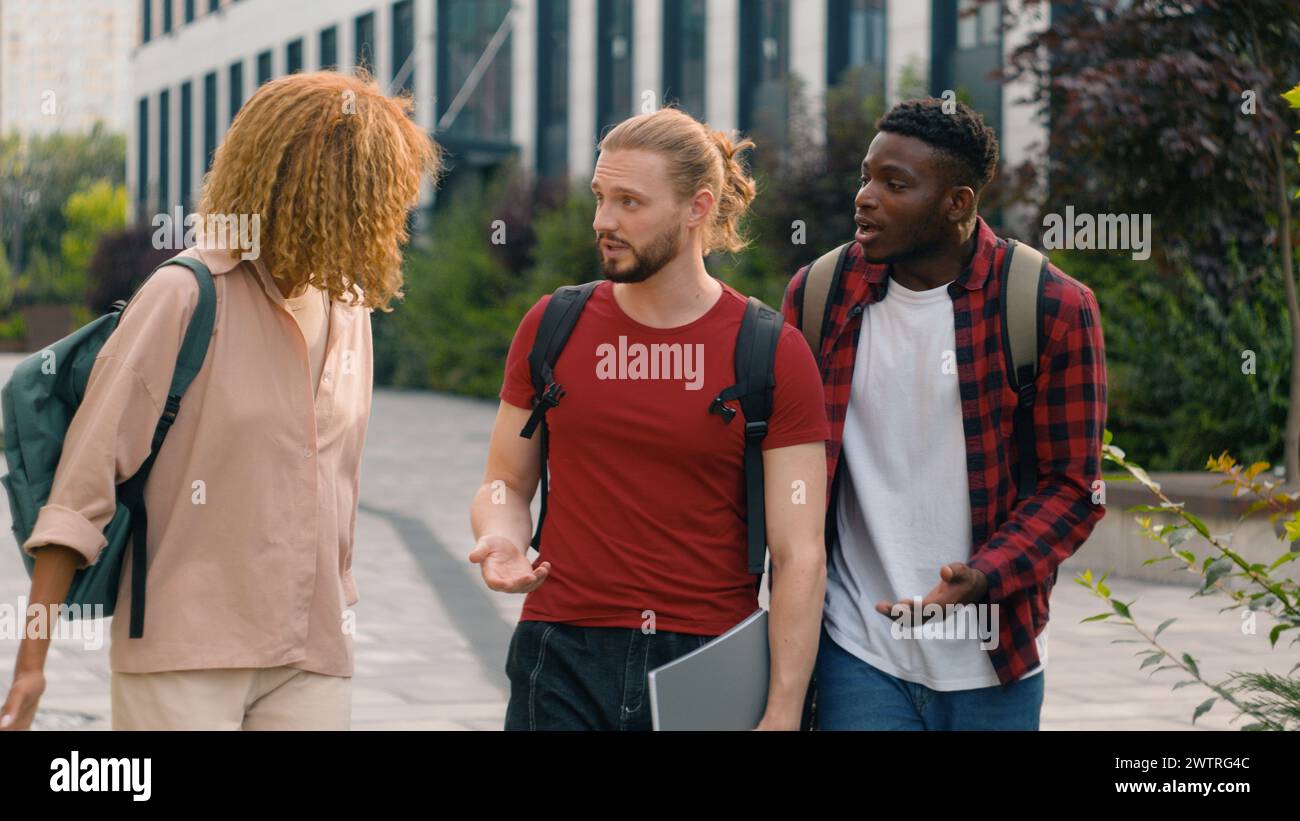 Group of mad emotional students multiracial friends Caucasian man guy with African American woman girl and ethnic guy diversity people walking Stock Photo