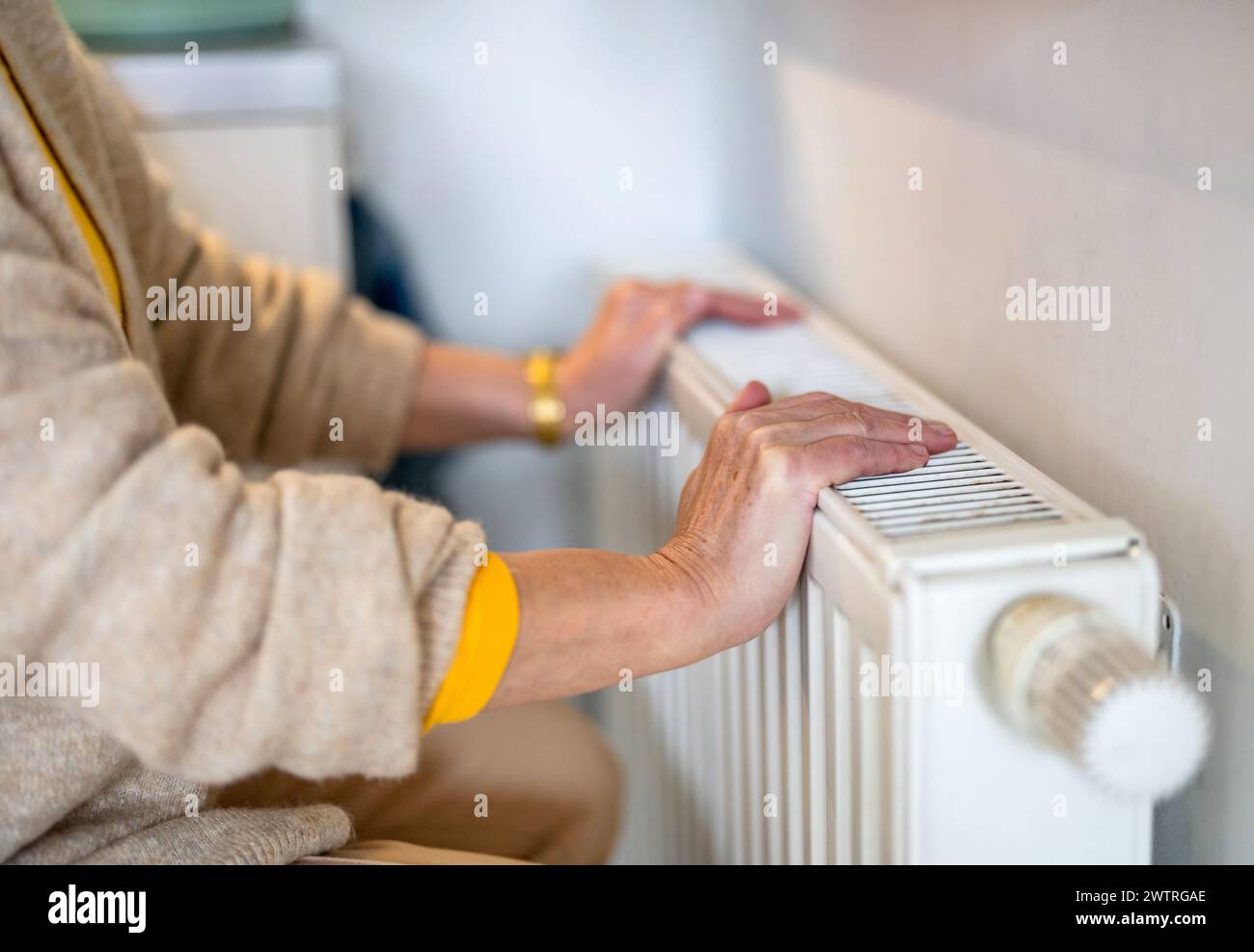 Senior woman checking heating radiator in her apartment Stock Photo