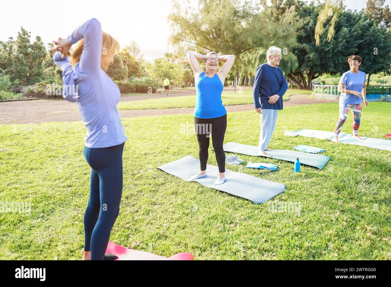 Multiracial senior people doing workout exercises outdoor with city park in background - Healthy and joyful elderly lifestyle concept - Focu Stock Photo