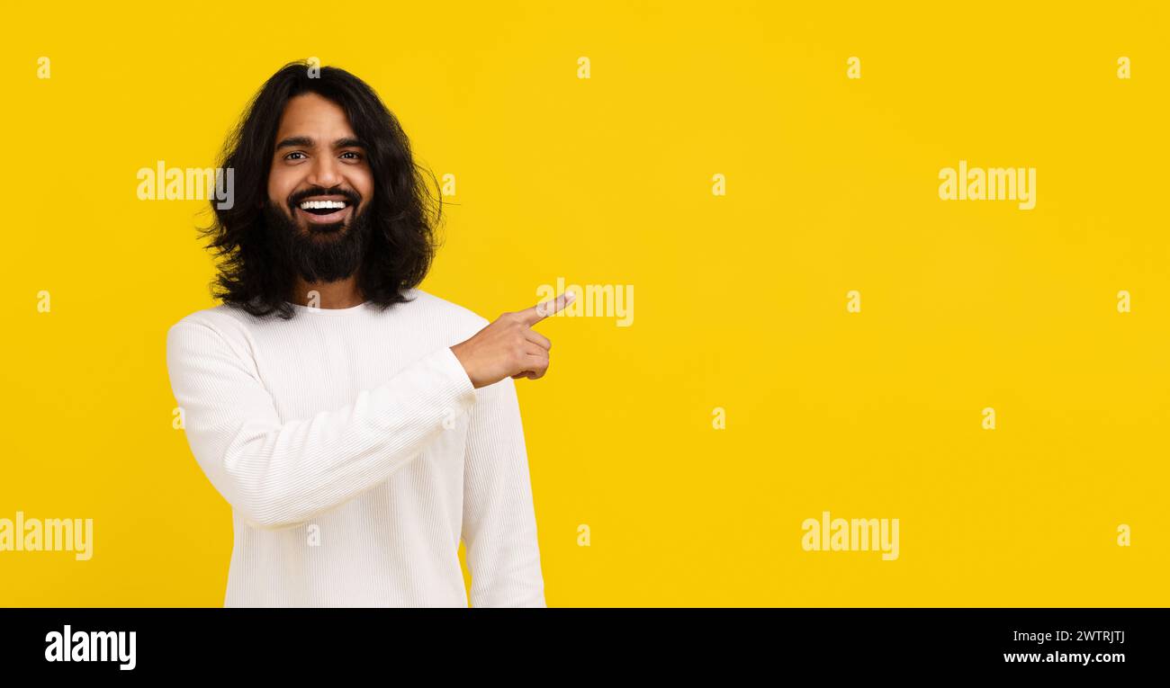 Cheerful young indian man pointing at copy space Stock Photo