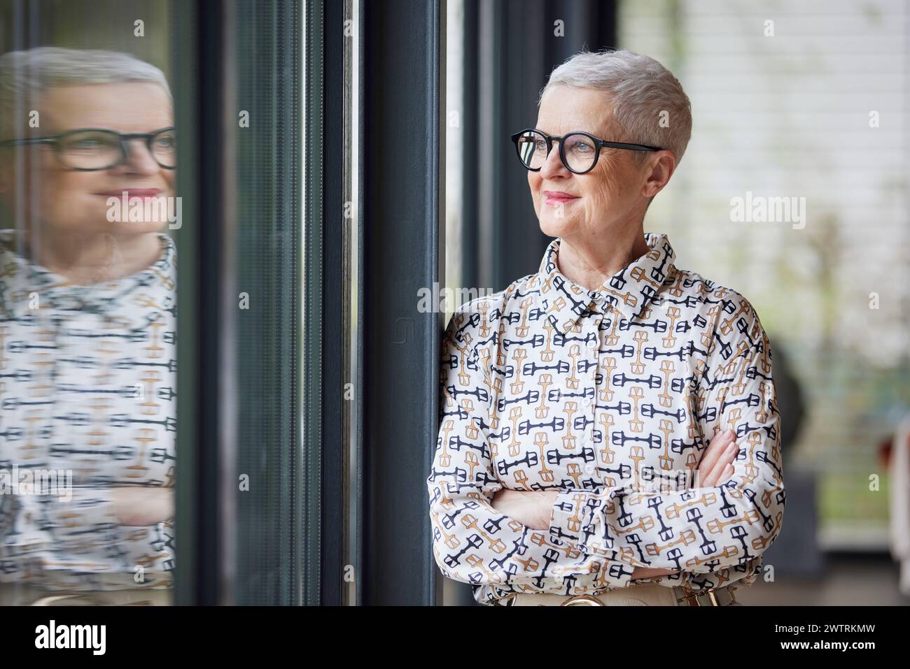 Senior woman at home looking out of window Stock Photo