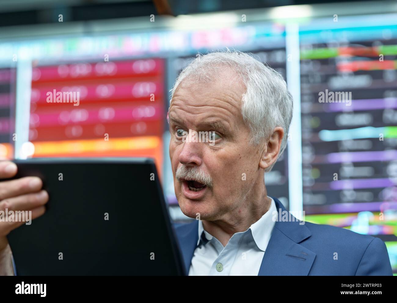 Senior trader looking shocked at his laptop. Stock Photo