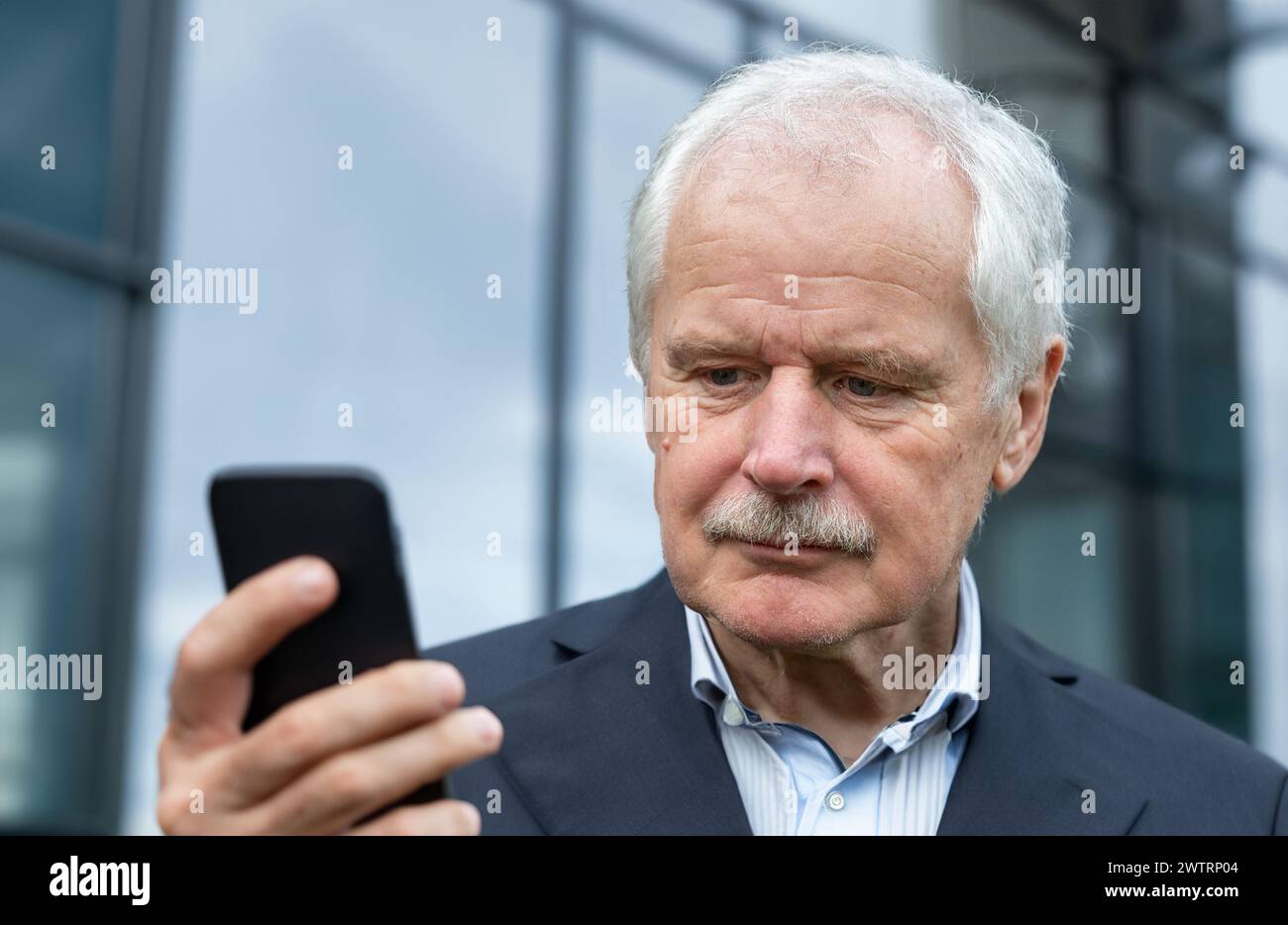 Senior Business man in a suit looking concentrated at his mobile phone Stock Photo