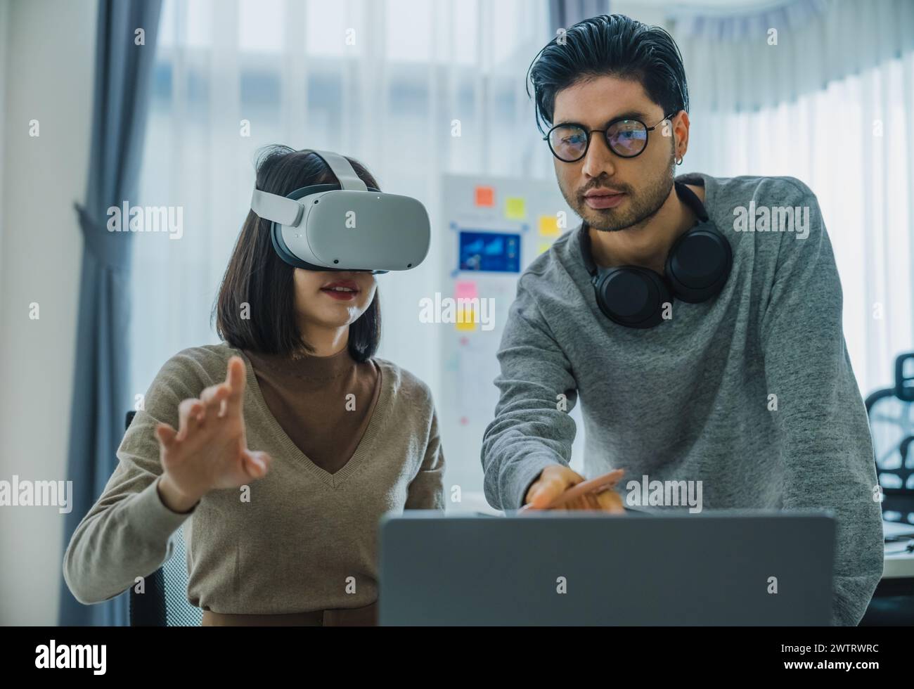 Asian and Indian developer program coding sent to virtual reality headset to implement ai project at office Stock Photo
