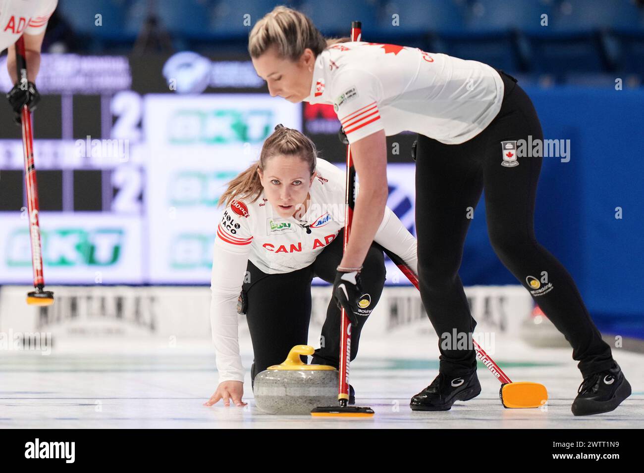 Canada skip Rachel Homan, left, delivers a stone against Italy as teammate Emma Miskew prepares