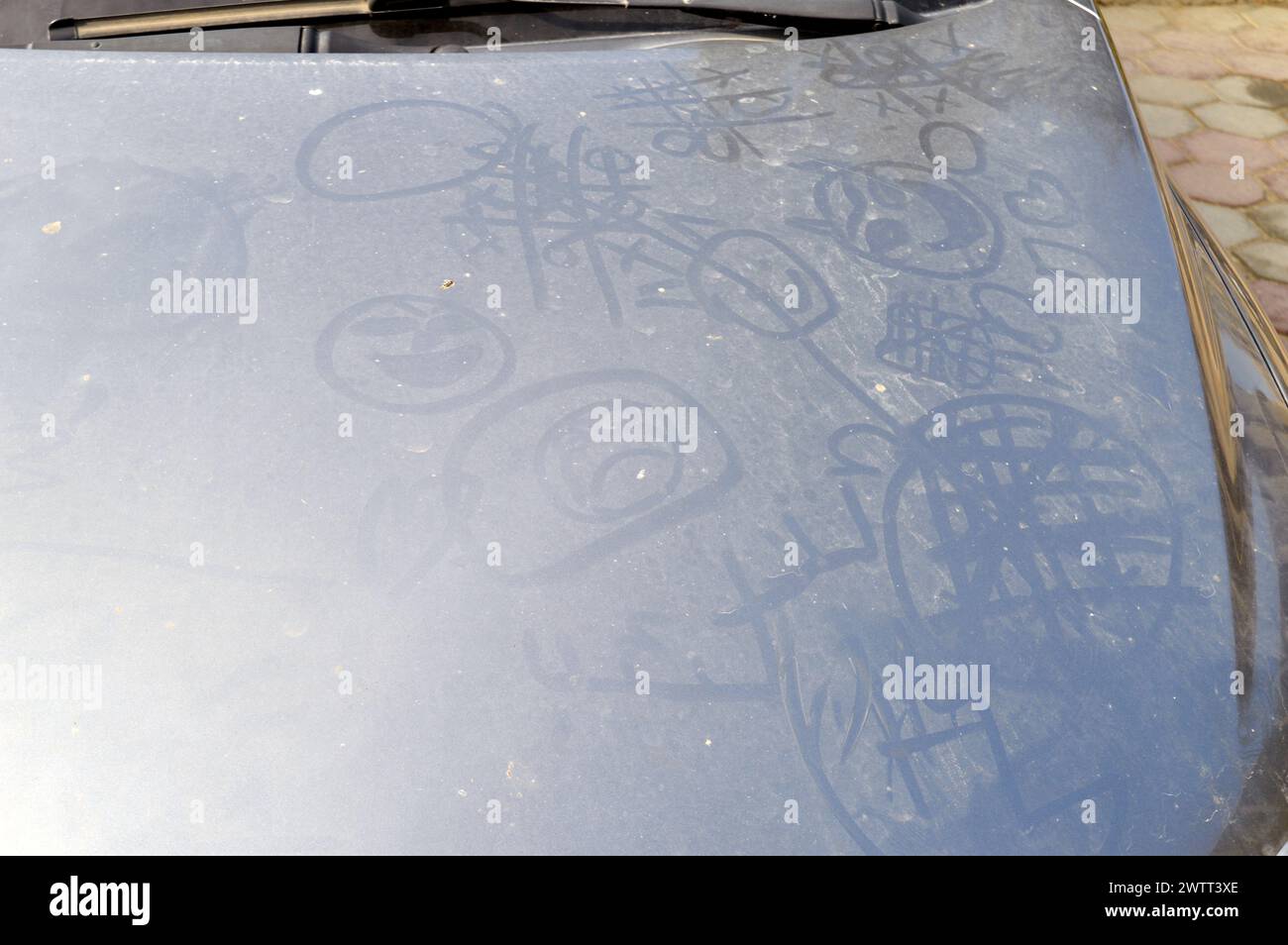 illustrations and kids' games on a dusty car engine hood, a dusty car with drawing on it done by children playing, a dusty vehicle, neglected car, sel Stock Photo