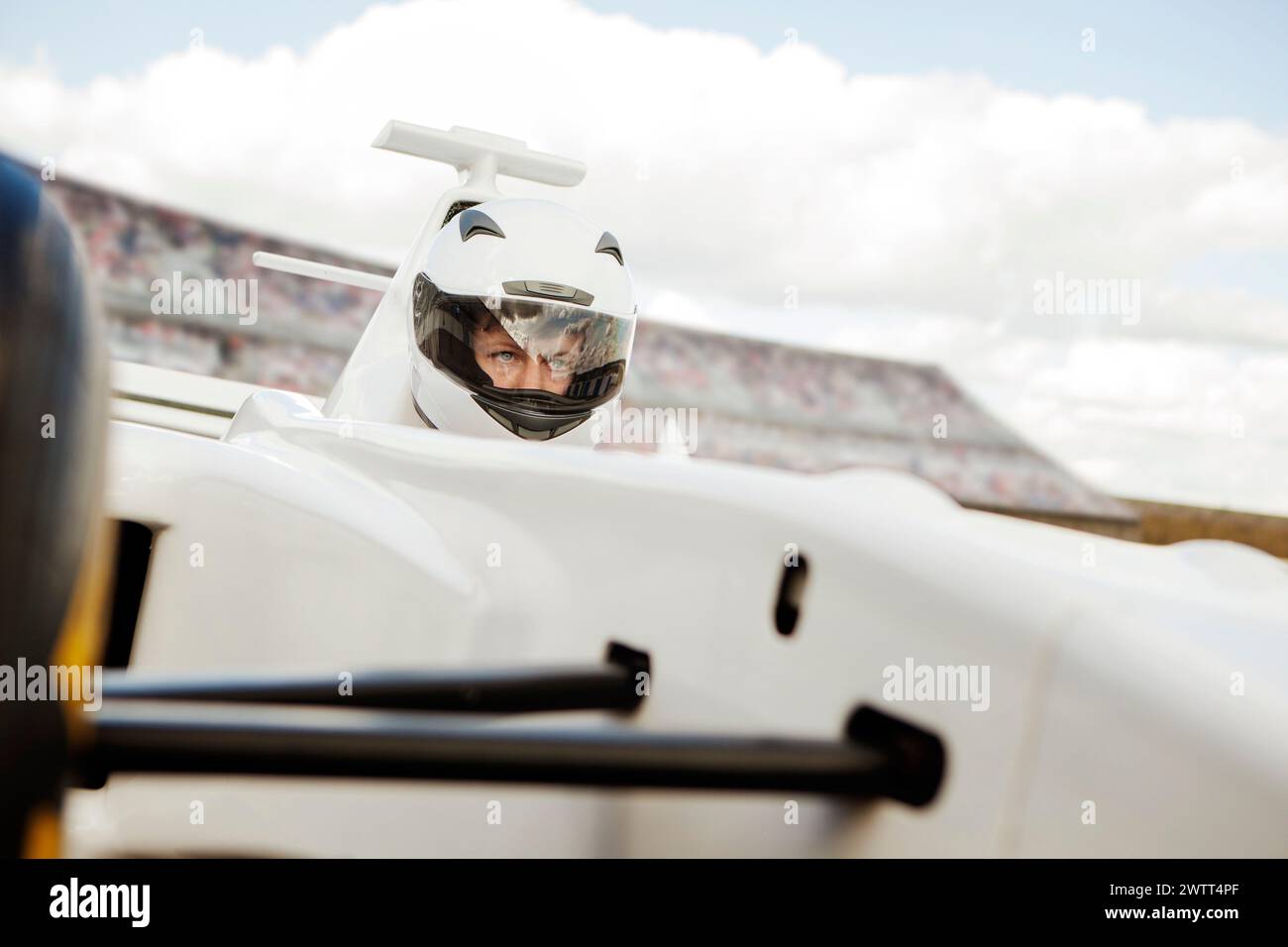 Race car driver focused behind the wheel at the racetrack. Stock Photo