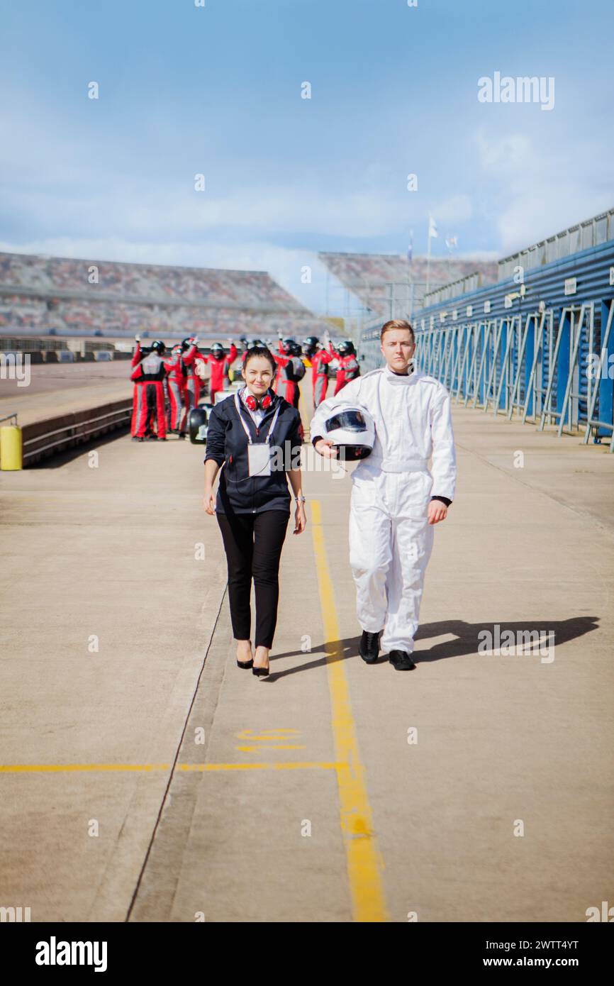 A confident astronaut in a white spacesuit walks alongside a professional woman on a launchpad. Stock Photo