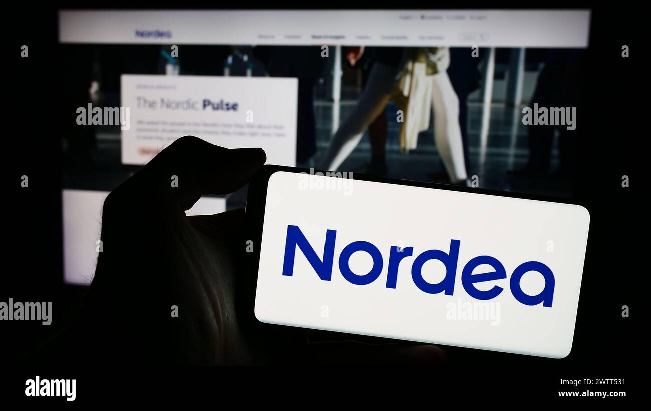 Person holding smartphone with logo of Finnish financial services company Nordea Bank Abp in front of website. Focus on phone display. Stock Photo